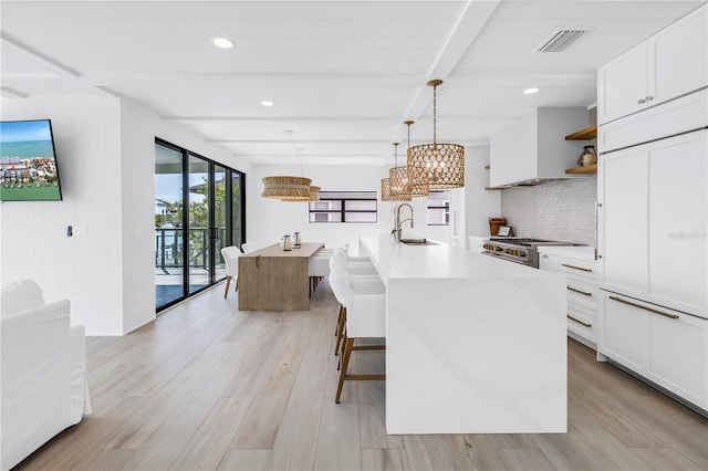 8505 Blind Pass Dr, Treasure Island, FL 33706 - kitchen featuring a sink, high end stove, tasteful backsplash, white cabinetry, and open shelves