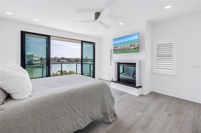 8505 Blind Pass Dr, Treasure Island, FL 33706 - bedroom with a glass covered fireplace, access to exterior, wood finished floors, recessed lighting, and baseboards