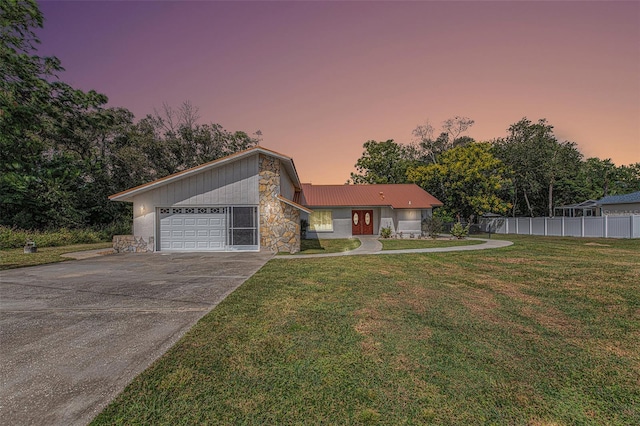 ranch-style house featuring a garage and a lawn