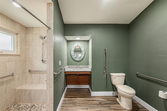 bathroom featuring a tile shower, vanity, and toilet