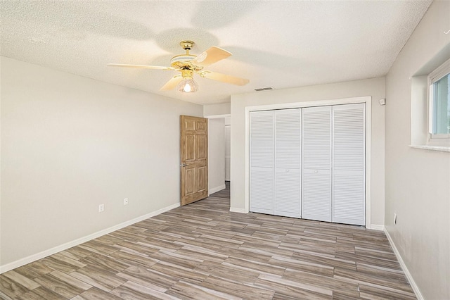 unfurnished bedroom featuring light hardwood / wood-style flooring, ceiling fan, a closet, and a textured ceiling