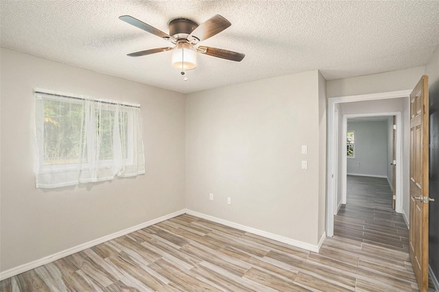 empty room featuring light hardwood / wood-style flooring, ceiling fan, and a textured ceiling