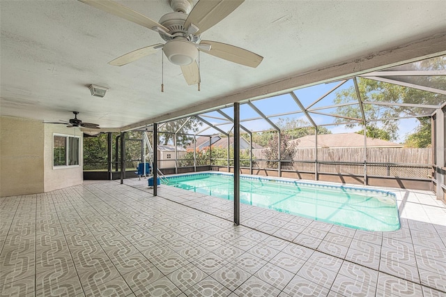 view of swimming pool with a patio, ceiling fan, and glass enclosure