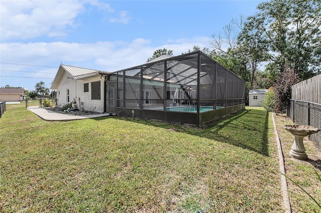 rear view of house featuring a patio area, a lawn, a shed, and glass enclosure