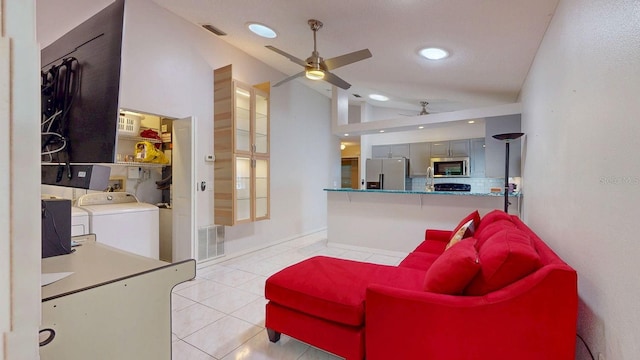 living area featuring lofted ceiling, ceiling fan, light tile patterned flooring, visible vents, and washer and clothes dryer