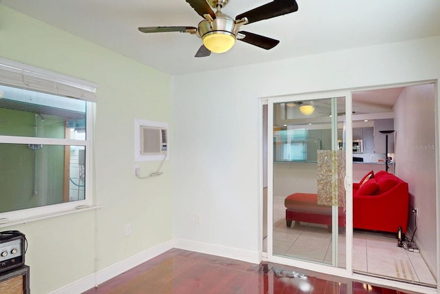 interior space featuring a ceiling fan, a wall mounted AC, baseboards, and wood finished floors