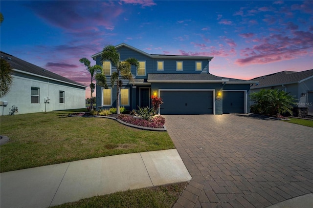 traditional-style house featuring a garage, a yard, and decorative driveway