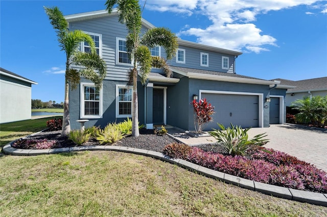 traditional home with decorative driveway, a front yard, and stucco siding