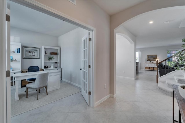 office space with arched walkways, baseboards, and light tile patterned floors