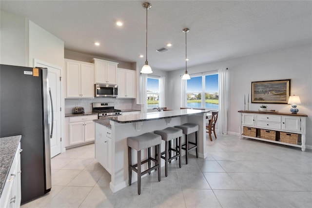 kitchen with pendant lighting, appliances with stainless steel finishes, a center island, and white cabinets