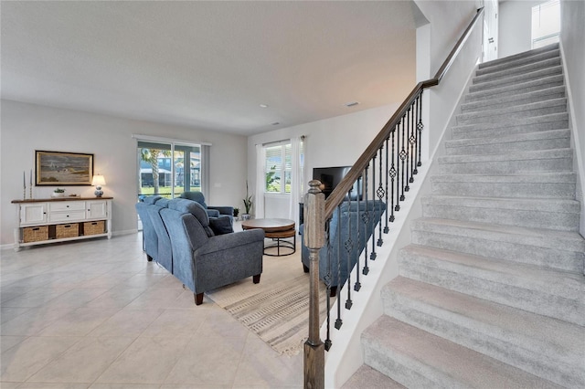 living room featuring stairs, light tile patterned flooring, and baseboards