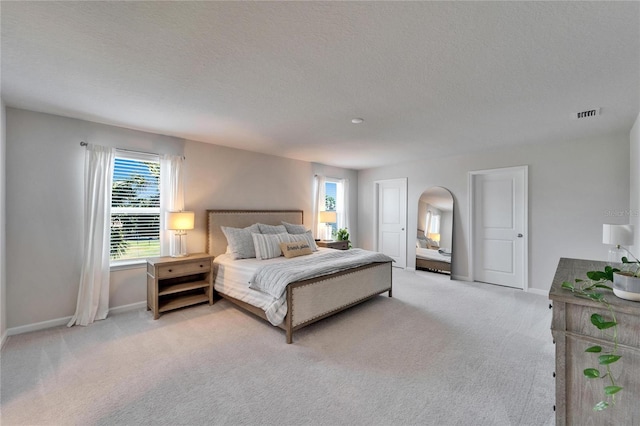 bedroom with arched walkways, light colored carpet, visible vents, and baseboards