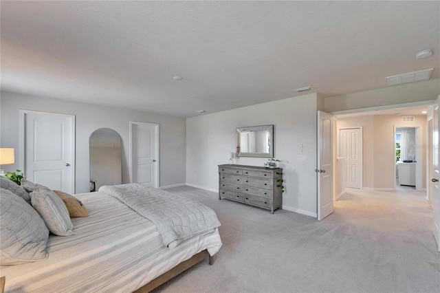 bedroom featuring arched walkways, baseboards, visible vents, and light colored carpet