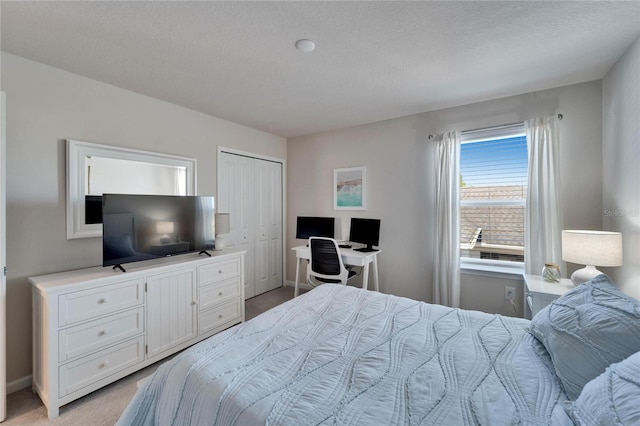 bedroom featuring a closet, baseboards, a textured ceiling, and light colored carpet