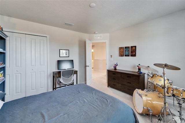 bedroom featuring light carpet, a textured ceiling, visible vents, and a closet