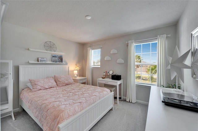 bedroom featuring light colored carpet, a textured ceiling, baseboards, and multiple windows