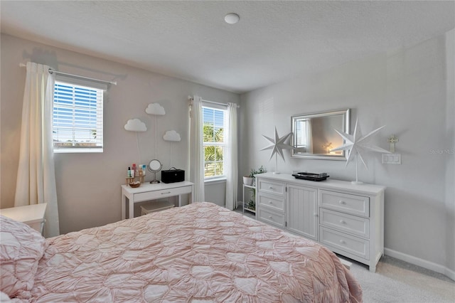 bedroom featuring light carpet, a textured ceiling, and baseboards