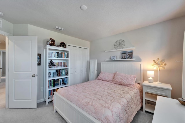 carpeted bedroom featuring a textured ceiling, a closet, and visible vents