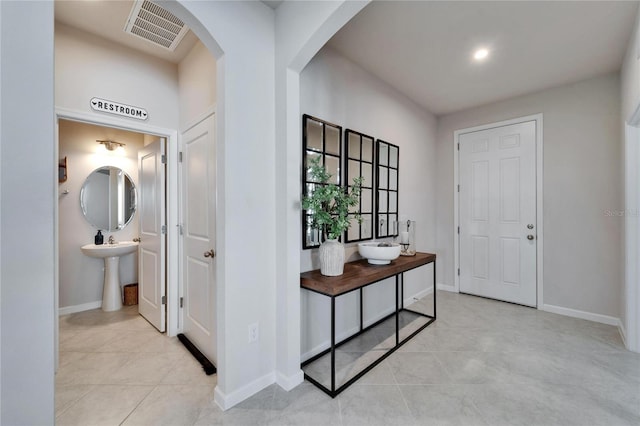 entryway featuring arched walkways, light tile patterned flooring, visible vents, and baseboards