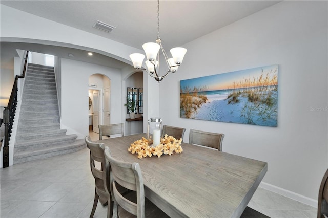 dining area featuring arched walkways, a chandelier, light tile patterned flooring, visible vents, and stairs