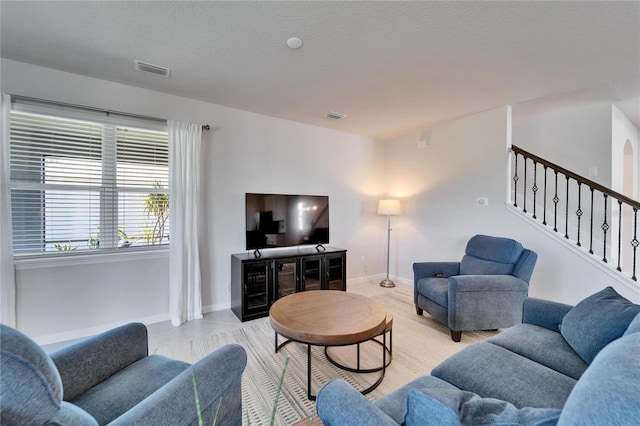 living area with visible vents, stairway, baseboards, and a textured ceiling