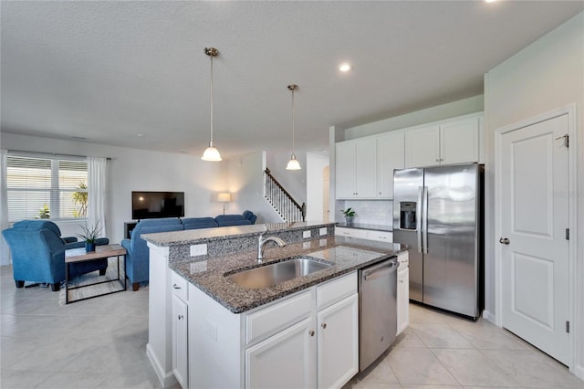 kitchen featuring a center island with sink, white cabinets, appliances with stainless steel finishes, open floor plan, and a sink