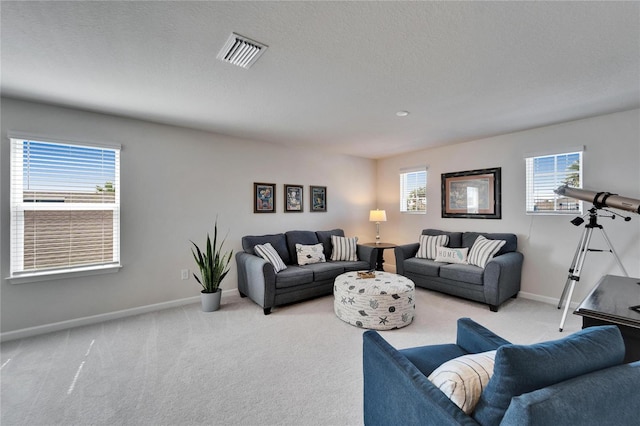 living area with light carpet, a textured ceiling, visible vents, and baseboards