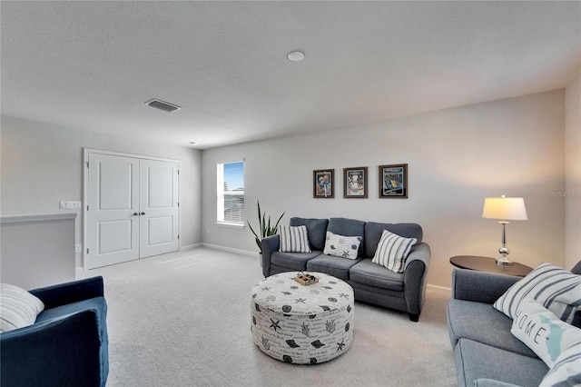 living room with baseboards, visible vents, a textured ceiling, and light colored carpet