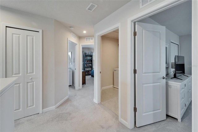 hallway with light carpet, baseboards, and visible vents