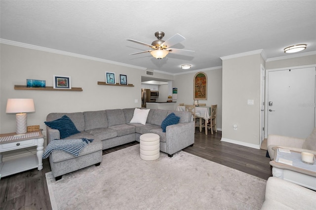 living room with ceiling fan, ornamental molding, dark wood-type flooring, and a textured ceiling