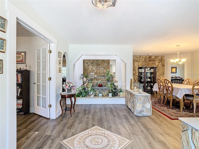 foyer entrance with arched walkways, wood finished floors, and a notable chandelier