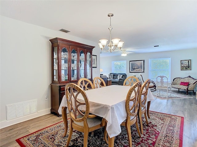 dining space with baseboards, a notable chandelier, visible vents, and wood finished floors