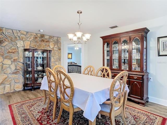 dining room with light wood-type flooring, visible vents, a chandelier, and baseboards