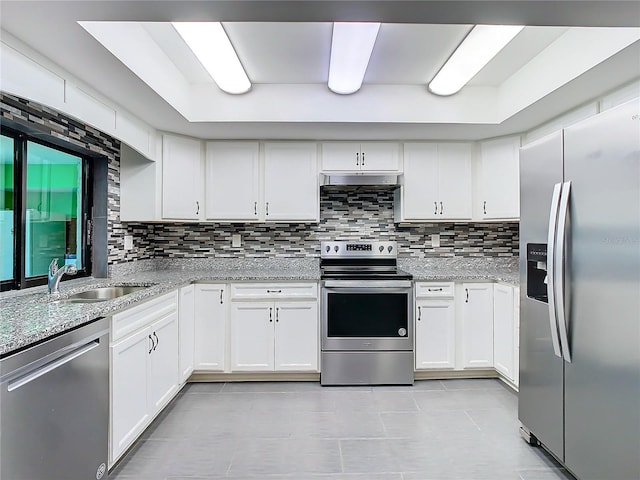 kitchen with light stone counters, stainless steel appliances, backsplash, white cabinets, and a sink