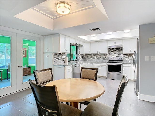 kitchen featuring tasteful backsplash, visible vents, stainless steel appliances, and a raised ceiling