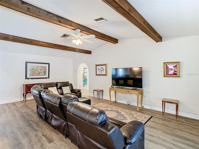 living area featuring arched walkways, ceiling fan, wood finished floors, visible vents, and baseboards