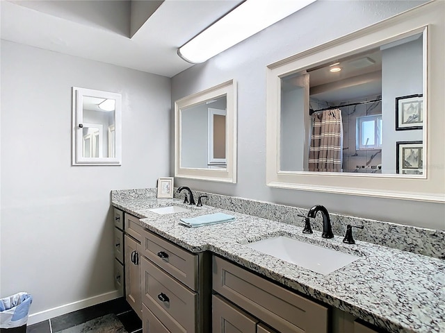 full bath with double vanity, baseboards, and a sink