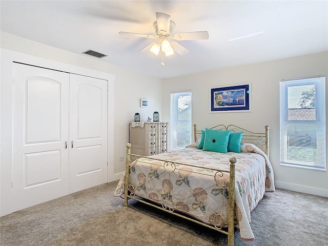 carpeted bedroom featuring baseboards, a closet, visible vents, and a ceiling fan