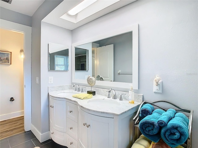 bathroom with a skylight, baseboards, visible vents, and a sink