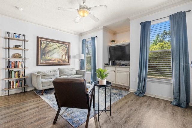 living area with a ceiling fan, a textured ceiling, wood finished floors, crown molding, and baseboards