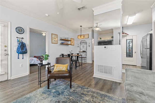 interior space featuring visible vents, wood finished floors, a ceiling fan, and ornamental molding