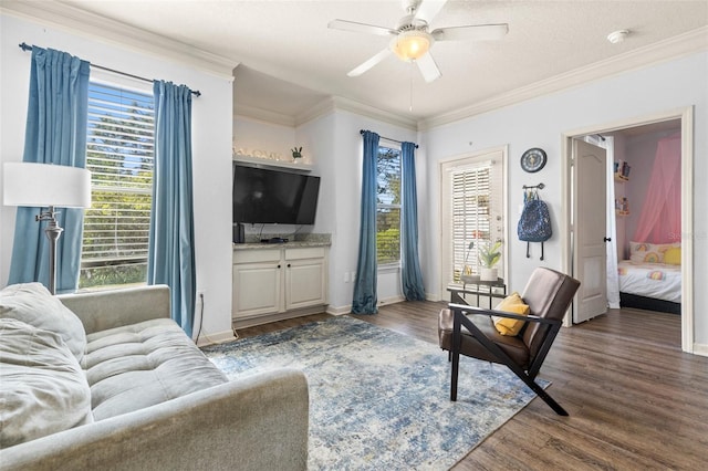 living area featuring ornamental molding, baseboards, a ceiling fan, and wood finished floors