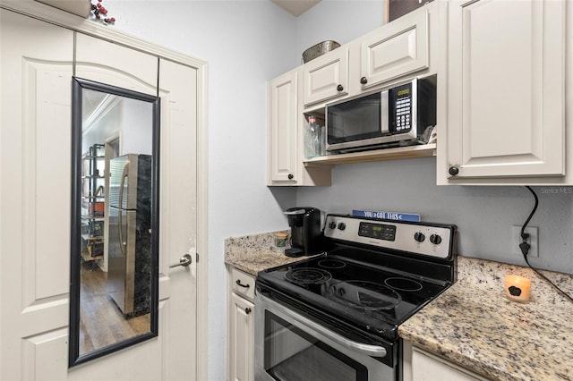 kitchen featuring stainless steel appliances, light stone countertops, and white cabinetry