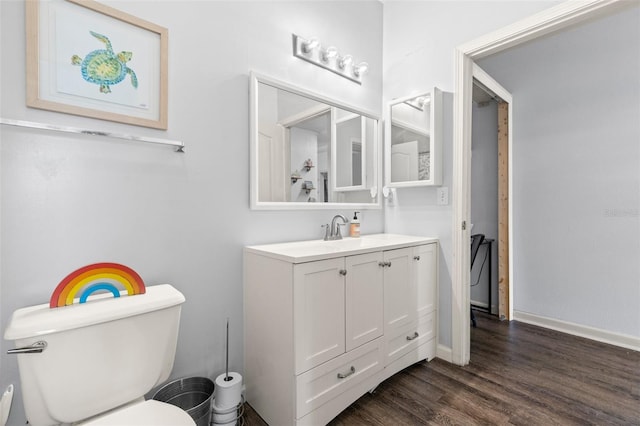 bathroom featuring toilet, vanity, baseboards, and wood finished floors