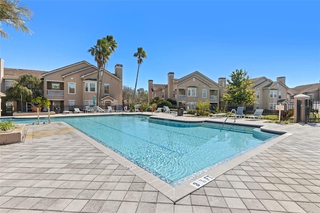 pool with a patio, fence, and a residential view