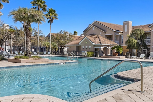 community pool with a patio area and fence