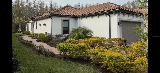 view of home's exterior featuring an attached garage, a tile roof, and stucco siding