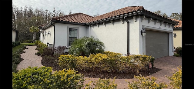 view of property exterior featuring a tile roof, an attached garage, and stucco siding