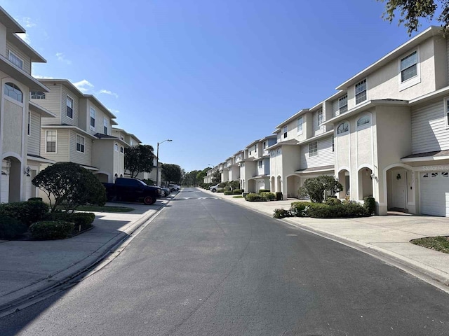 view of street featuring sidewalks, street lighting, a residential view, and curbs