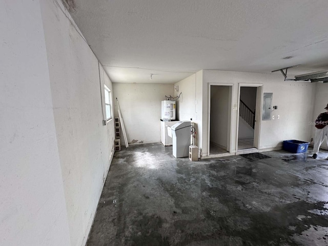 spare room with concrete flooring, a textured ceiling, water heater, stairway, and electric panel